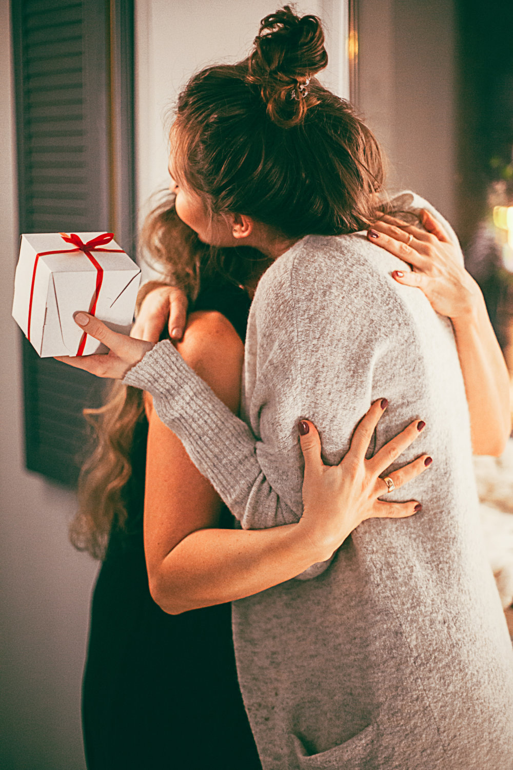 two women hugging each other, one with present on her hand