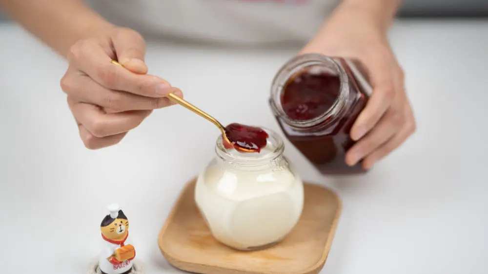 homemade yogurt with hands putting jam on top